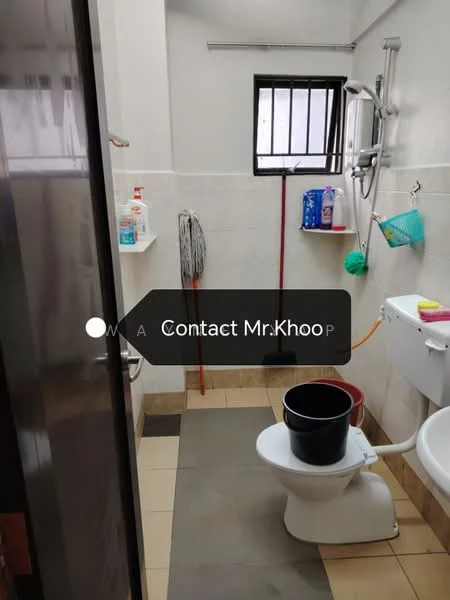 Bathroom features: white tiled walls, cream tiled flooring, toilet, sink with wall-mounted faucet, mirror above sink, shower area with glass door, mop and broom visible, bucket, hanging storage basket, window for natural light.