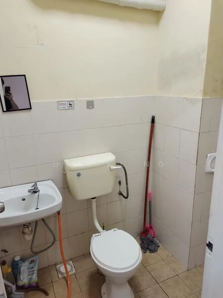 Bathroom features: white ceramic toilet, white flush tank, small sink with chrome faucet, white tiled walls, beige tiled flooring, cleaning supplies visible, mop, broom, mirror on wall.