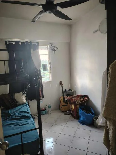 Bedroom features: single bed with blue bedding, black metal bed frame, white painted walls, white tiled flooring, ceiling fan, window with metal grille, guitar, woven storage basket, blue plastic bag, clothes hanging on the door, small wall-mounted light.
