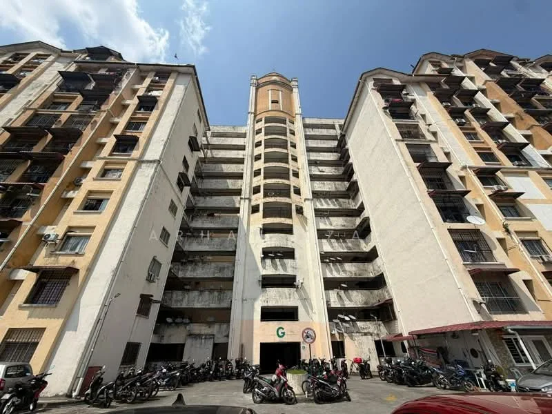 Exterior type: mid-rise condominium; features: yellow painted facade, exposed concrete sections, multiple balconies, parking area with motorcycles, 5-storey building, main entrance with signage, fire escape stairs, windows with metal grilles; style: modern.