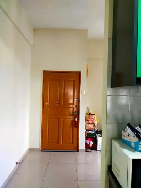 Room features: brown wooden door, white painted walls, grey tiled flooring, storage boxes, plastic bags, visible corner of kitchen cabinetry, light switch, door handle.