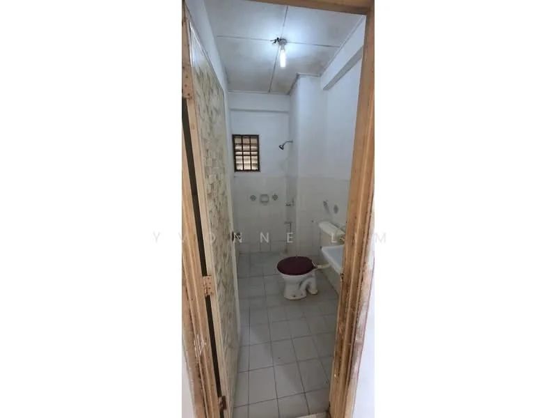 Bathroom features: white tiled walls, grey tiled flooring, one-piece toilet, chrome basin mixer faucet, shower head, small window for ventilation, light bulb fixture, toilet paper holder.