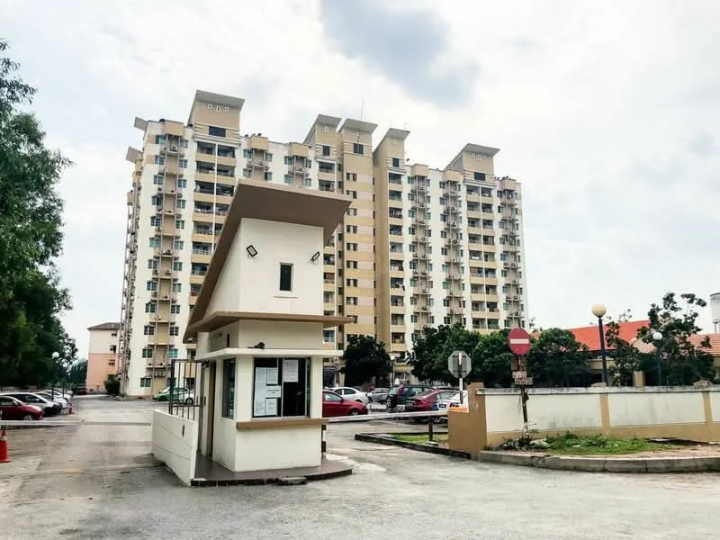 Exterior type: mid-rise condominium; features: guard house at entrance, multiple storeys, cream painted facade, balconies on upper floors, parking lot visible, landscaped area with trees, street signage, street lighting, surrounded by greenery; style: modern.