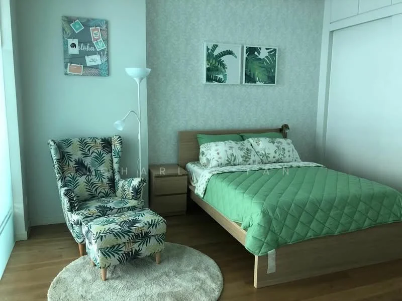Bedroom features: king-size bed with green quilted cover, floral patterned bedding, wooden bed frame, green accent wall with leaf pattern, light wood flooring, white built-in wardrobe, framed artwork with botanical prints, round area rug, green upholstered armchair with floral pattern, floor lamp; style: modern.