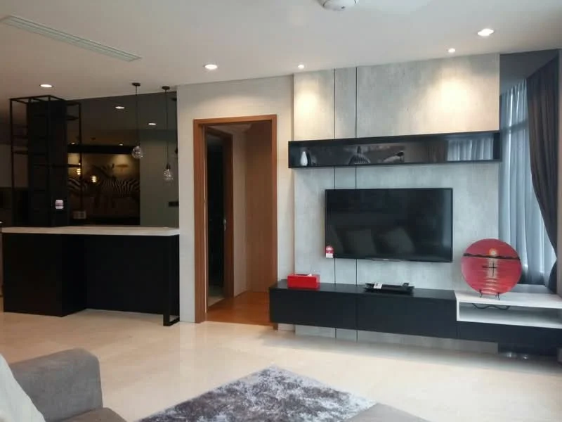Living features: cream marble flooring, grey accent wall, black TV console, wall-mounted TV, recessed downlights, 5-blade ceiling fan, large windows with sheer curtains, decorative red vase, area rug with geometric pattern, open-plan layout to kitchen, wooden door leading to hallway, black shelving unit with pendant lights; style: modern.