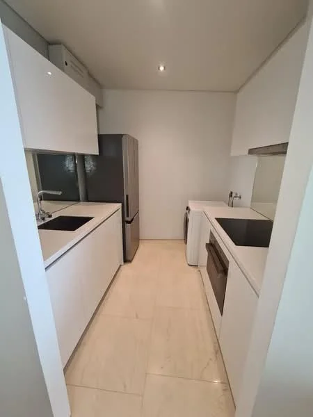 Kitchen features: white cabinetry, double-bowl stainless-steel sink, chrome pull-down faucet, black countertop, built-in oven, freestanding fridge, white walls, marble tile flooring, recessed downlights, washer/dryer combo, sliding window, modern design; style: modern.