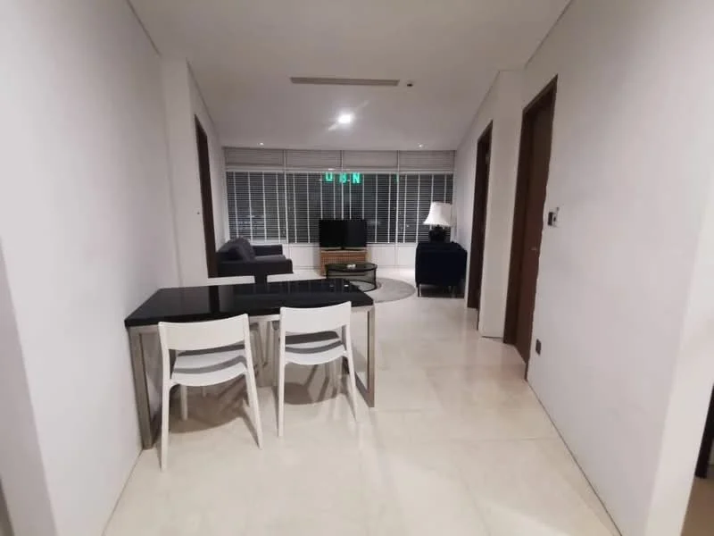 Living features: white painted walls, cream tiled flooring, floor-to-ceiling windows, black glass dining table, 2 white plastic dining chairs, sofa in dark grey fabric, TV console, wall-mounted TV, table lamp, recessed downlights; style: modern.
