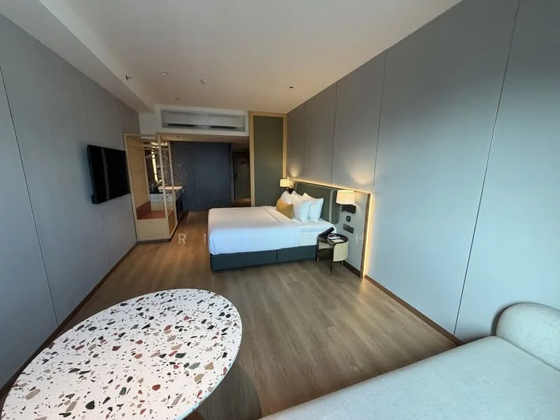 Bedroom features: king-size bed with white bedding, upholstered headboard, 2 bedside lamps, wall-mounted TV, wooden flooring, grey painted walls, recessed lighting, sofa with light fabric, decorative coffee table with speckled surface, air conditioning unit, built-in wardrobe, large window with natural light; style: modern.