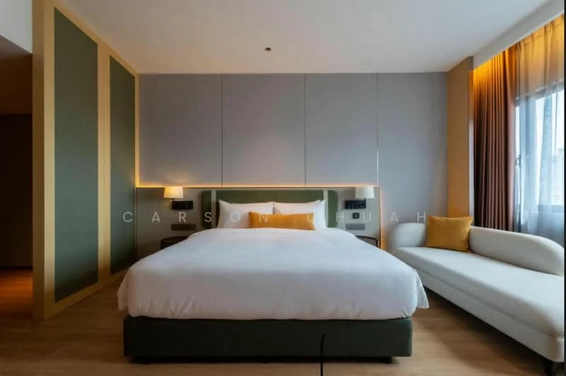 Bedroom features: king-size bed with upholstered headboard, white bedding, light wood flooring, grey accent wall, green upholstered bed frame, two wall-mounted bedside lamps, sofa with yellow cushion, floor-to-ceiling window with sheer curtains, decorative wall paneling, recessed lighting, wooden side table; style: modern; view: city.