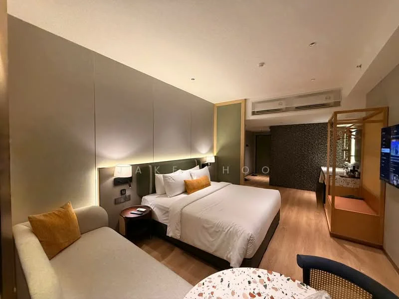 Bedroom features: king-size bed with white bedding, upholstered headboard, sofa with beige upholstery and orange cushion, wooden flooring, recessed downlights, wall-mounted TV, decorative mirror, built-in wardrobe, side table with lamp, desk with chair, air conditioning unit; style: modern.