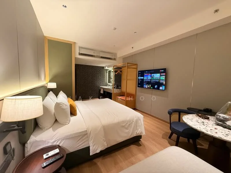 Bedroom features: queen-size bed with white bedding, upholstered headboard, 2 bedside lamps, wall-mounted TV, wooden flooring, air conditioning unit, built-in wardrobe, small round dining table, blue upholstered chair, decorative wall panel, wall-mounted mirror, remote control on bedside table; style: modern.