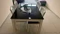 Dining features: black granite dining table, 4 transparent acrylic dining chairs, decorative centerpiece on table, white walls, tile flooring, large window with natural light; style: modern.
