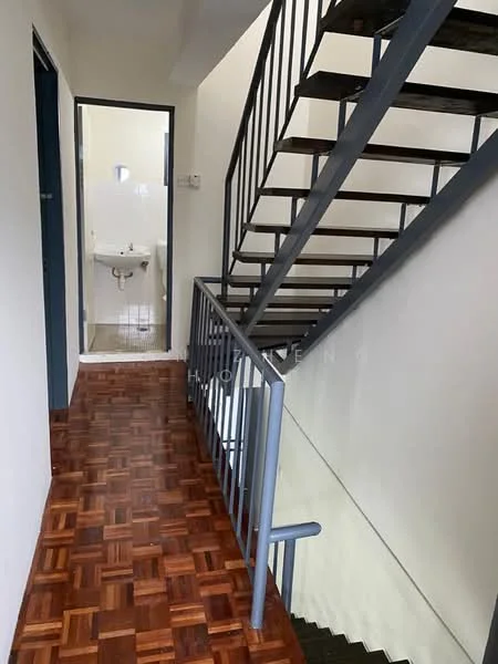 Hallway features: wooden parquet flooring, metal railing, staircase with metal steps, white painted walls, doorway leading to bathroom, light fixture on ceiling; style: modern. Bathroom features: white sink, toilet, mirror, tile flooring, white tiled walls.