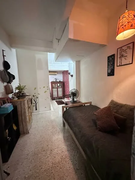 Living features: sofa with dark upholstery, decorative pillows, wooden coffee table, floor fan, wall-mounted artwork, light fixture with patterned shade, exposed ceiling beams, polished concrete flooring, white painted walls; style: minimalist.