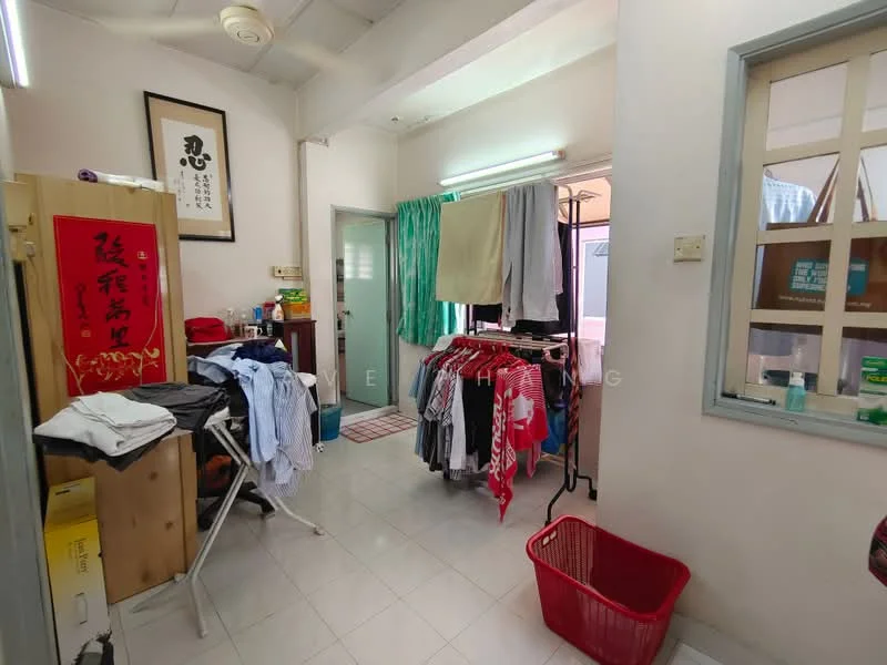 Laundry features: white tiled flooring, light-colored walls, ceiling fan, window with grid design, clothes drying rack, red laundry basket, ironing board, clothes hanging on rack, doorway leading to another room, framed artwork on wall.
