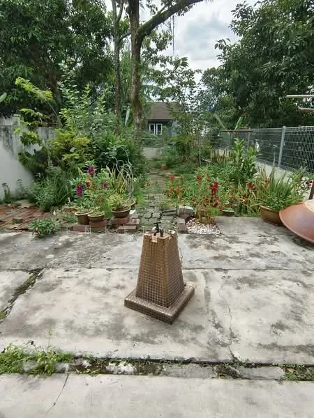 Exterior type: landscape garden; features: concrete patio, flower beds with various plants, potted plants, fenced perimeter, lush greenery, garden area with flowers, decorative water feature, natural stone pathway; style: tropical-modern.