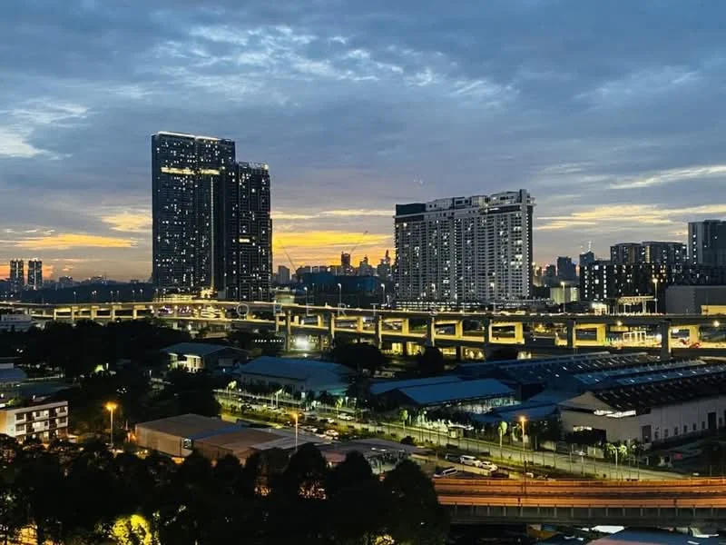 Exterior type: high-rise condominium; features: city skyline view, multiple high-rise buildings, highway overpass, urban landscape, evening lighting, cloudy sky, streetlights visible, commercial buildings in foreground; style: modern.