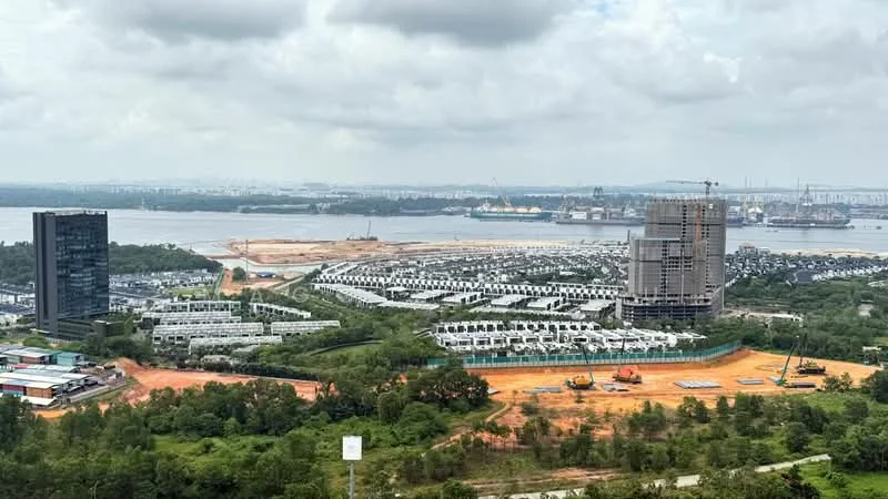 Exterior type: high-rise condominium; features: city skyline view, construction site in foreground, waterfront view, mixed-use development, surrounding greenery, multiple residential units, industrial area in background; style: modern.