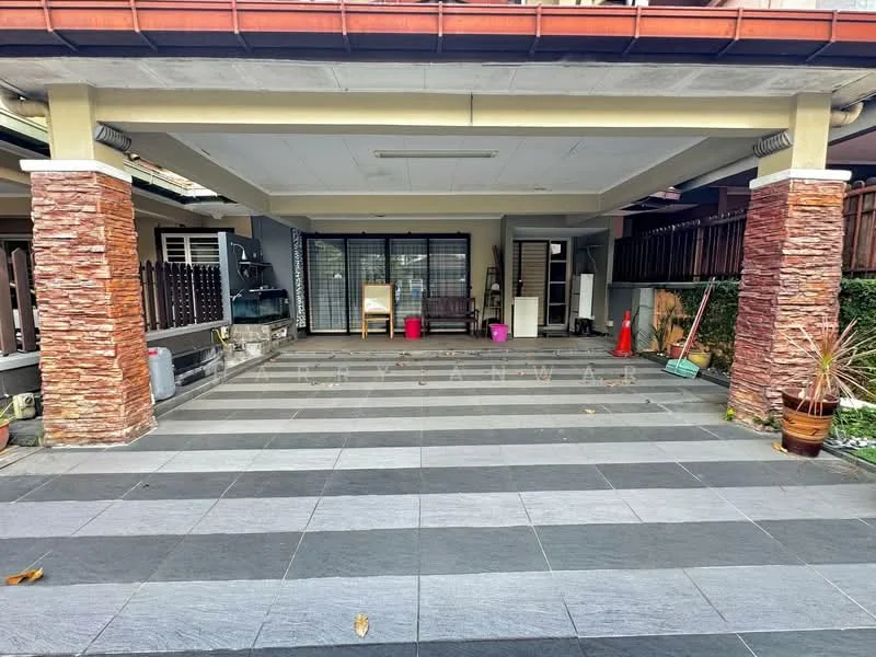 Exterior type: car porch; features: stone-clad columns, grey stone flooring, covered area, paved surface, visible outdoor furniture, decorative plants, surrounding greenery, safety cones, clean and well-maintained, open space; style: modern.