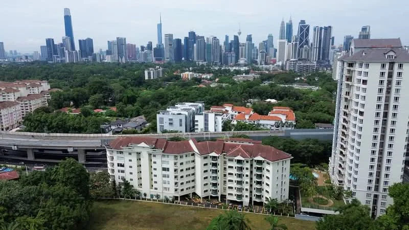 Exterior type: low-rise apartment block; features: white painted facade, red tiled roof, surrounded by greenery, landscaped garden, swimming pool visible, nearby highway, urban skyline in background, multiple storeys, balconies on upper floors; style: modern.