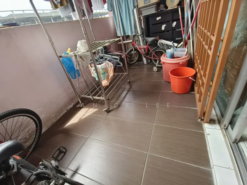 Room features: brown ceramic tile flooring, metal drying rack, bicycle, plastic storage container, orange bucket, wooden sliding door, clothes hanging on rack, black storage cabinet.