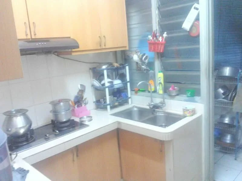 Kitchen features: laminate cabinetry in light wood, white tiled backsplash, double-bowl stainless-steel sink, chrome pull-down faucet, 4-burner gas hob, stainless-steel range hood, countertop with rounded edges, open shelving for utensils, metal pots and pans visible, cleaning supplies on countertop, kitchen utensils in a basket, window with metal grilles; style: functional.