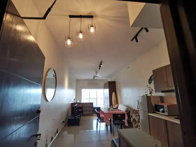 Living features: 3-blade ceiling fan, pendant lighting with three bulbs, white painted walls, grey tiled flooring, large window with natural light, sofa, dining table with chairs, wooden cabinetry, microwave, kitchen counter, decorative plants, mirror on wall; style: modern.