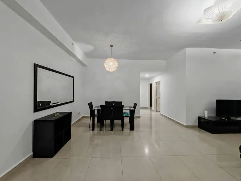 Living features: white painted walls, glossy tile flooring, ceiling light fixture, dining table with four chairs, black console table, black TV cabinet, wall-mounted TV, mirror on wall; style: modern.