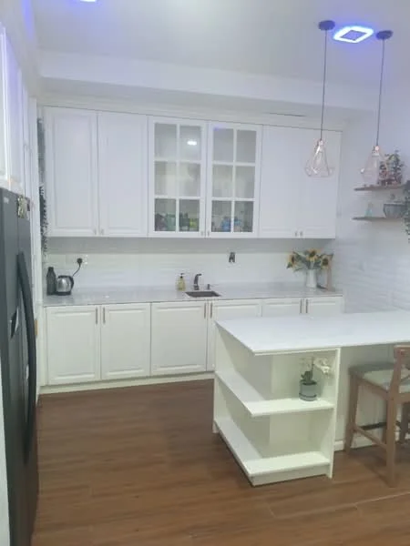 Kitchen features: white shaker cabinets, white countertop, stainless-steel sink, chrome pull-down faucet, built-in microwave, black refrigerator, pendant lights, tile backsplash, wood laminate flooring, open shelving, bar seating area; style: modern.