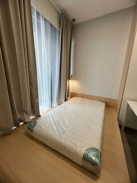 Bedroom features: single bed with mattress, light wood platform bed, floor-to-ceiling window, sheer curtains, solid wall, laminate flooring, wall-mounted lamp, neutral wall color; style: modern.