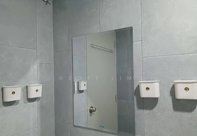 Bathroom features: grey tile walls, large mirror, white wall-mounted soap dispensers, door with handle, shelf above door; style: modern.