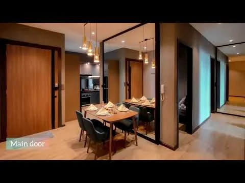 Dining features: wooden dining table, 4 upholstered dining chairs, pendant lighting above table, mirrored wall, light wood flooring, neutral painted walls, wall-mounted intercom, open kitchen view, decorative table setting; style: modern. Kitchen features: black cabinetry, stainless-steel appliances, kitchen countertop, kitchen island, recessed lighting; style: modern. Hallway features: wooden door, light wood flooring, neutral painted walls, recessed lighting; style: modern.
