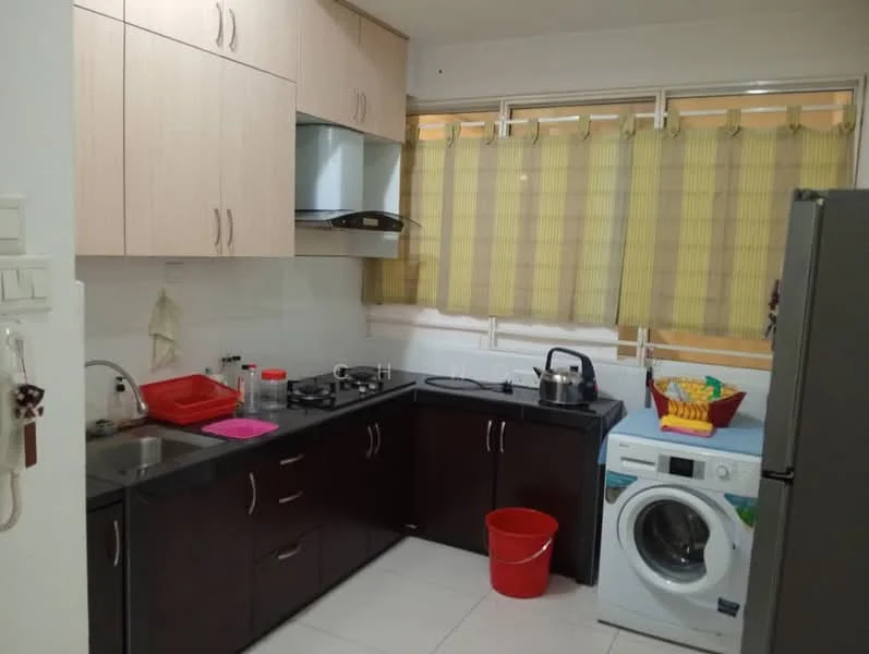 Kitchen features: light wood cabinetry, dark wood lower cabinets, black countertop, stainless-steel gas stove with two burners, stainless-steel range hood, built-in washing machine, red plastic bucket, white ceramic sink, kettle on stove, red plastic tray, window with yellow sheer curtains, white tiled walls, white tiled flooring; style: modern.