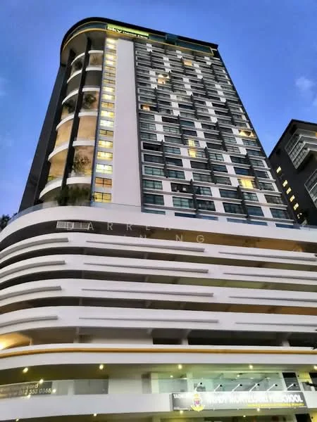Exterior type: high-rise condominium; features: glass curtain wall, white painted facade, projecting balconies, illuminated windows, signage at ground level, multiple storeys, modern architectural design, landscaped entrance, parking area visible, night lighting; style: modern.