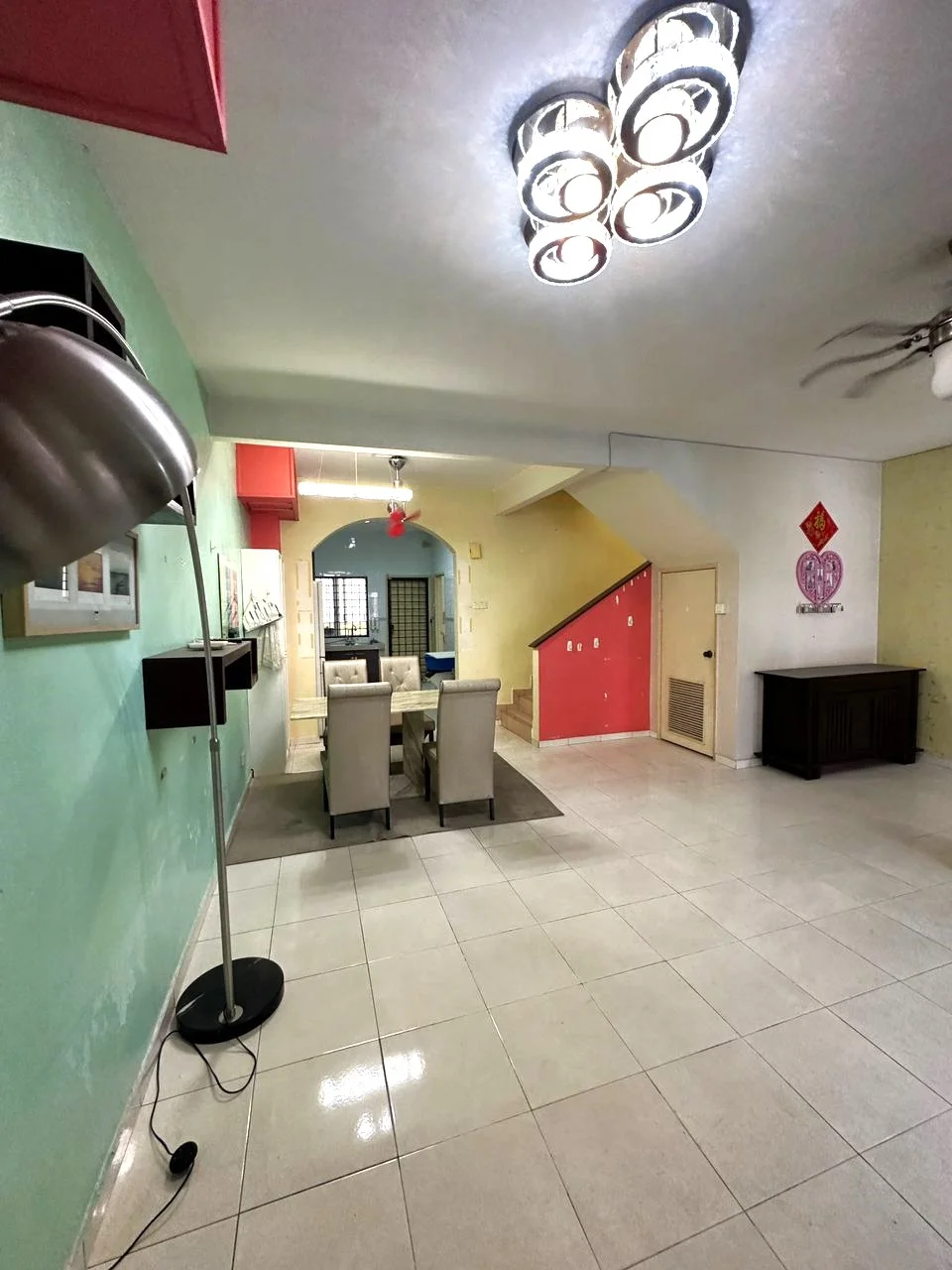 Living features: white tiled flooring, green painted walls, pink accent wall, dining table with four chairs, ceiling fan with light, recessed downlights, floor lamp, wall-mounted artwork, staircase leading to upper floor, wooden sideboard, open layout; style: modern.