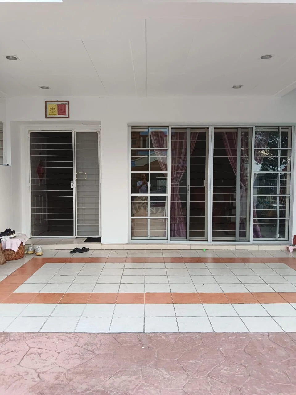 Exterior type: linked terrace house; features: sliding glass doors, security grills on doors, tiled flooring with decorative pattern, overhang roof, outdoor space, front porch area; style: modern.