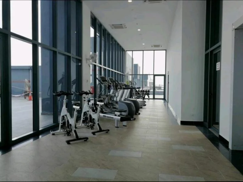 Gym features: exercise bikes, elliptical machines, treadmills, large floor-to-ceiling windows, tile flooring, air conditioning units, mirrored wall, fitness equipment, natural light, open layout; style: modern; view: city.