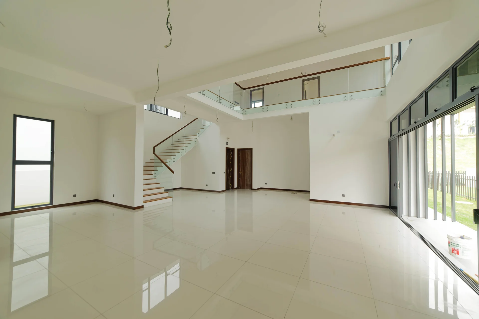 Room features: white painted walls, polished ceramic tile flooring, large floor-to-ceiling windows, glass railing staircase, high ceiling, open layout, natural light, sliding glass door, recessed downlights; style: modern; view: garden.