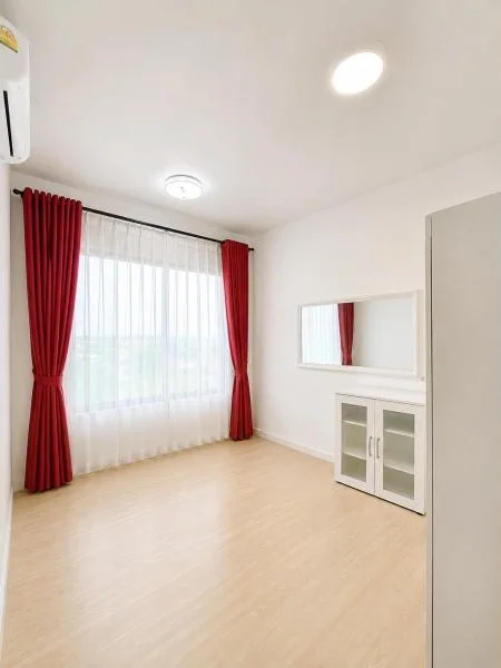 Bedroom features: white painted walls, light wood laminate flooring, large window, sheer white curtains, red blackout curtains, white ceiling, flush ceiling light, wall-mounted split air conditioner, rectangular wall mirror, white storage cabinet with glass doors, minimalist built-in storage, plain white door; style: minimalist.