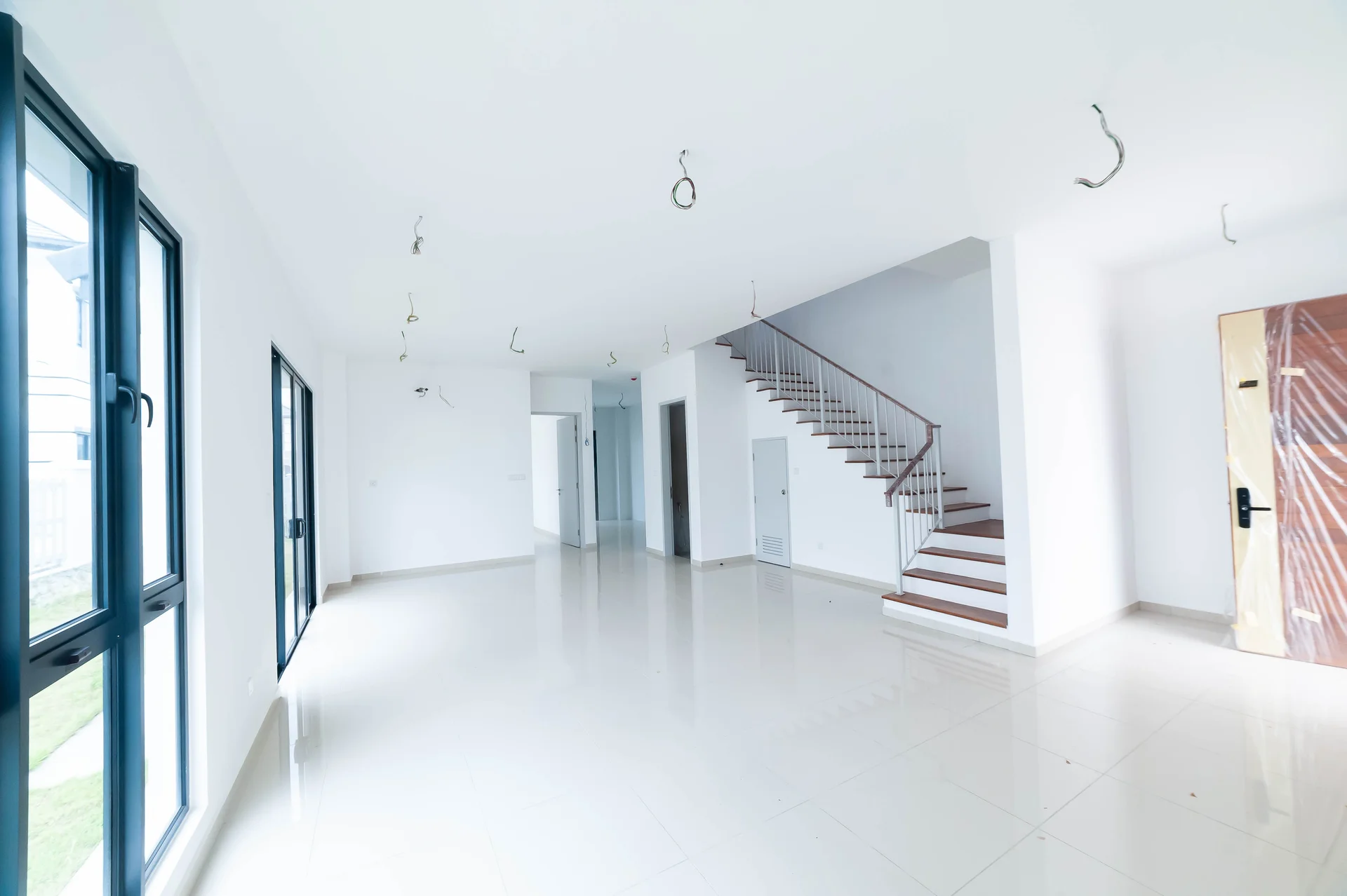 Living features: white painted walls, glossy ceramic tile flooring, floor-to-ceiling windows, staircase with wooden steps, open layout, recessed ceiling lights, door with black handle, multiple electrical outlets; style: modern; view: garden.