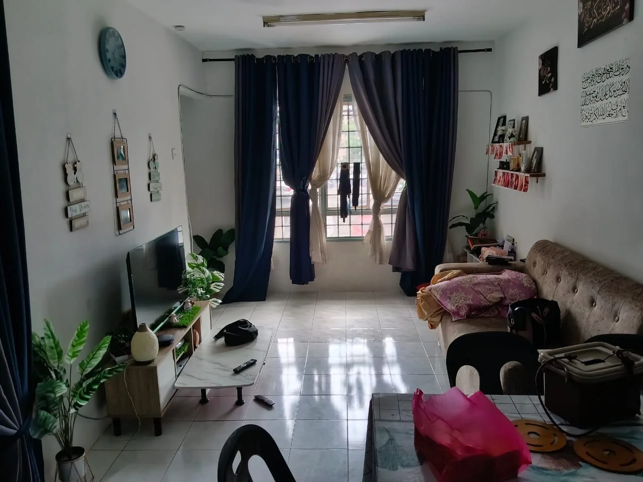 Living features: sofa in beige, coffee table, wall-mounted TV, floor-to-ceiling windows, sheer curtains, dark blue curtains, decorative wall shelves, houseplants, tile flooring, decorative wall art, area rug, light fixture on ceiling; style: modern; view: garden.