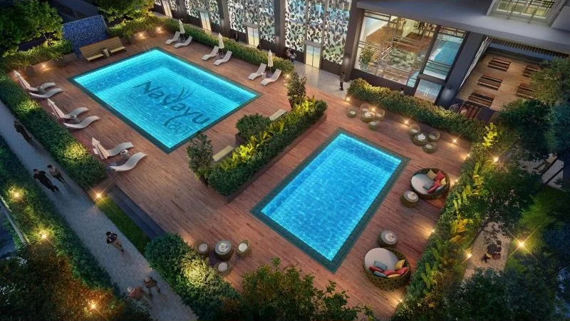 Exterior type: swimming pool deck; features: infinity pool, lap pool, wooden deck flooring, poolside loungers, landscaped greenery, outdoor seating areas with cushions, decorative lighting, surrounding hedges, water feature with logo; style: modern.