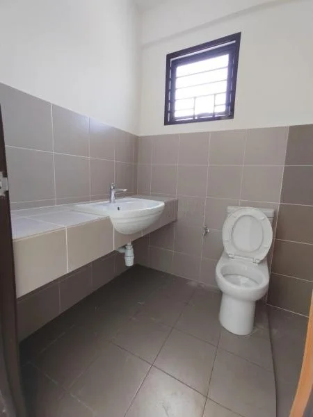 Bathroom features: white ceramic toilet, single-sink vanity with countertop, chrome basin mixer faucet, grey tiled walls, dark grey floor tiles, window with metal grille, mirror above sink; style: modern.