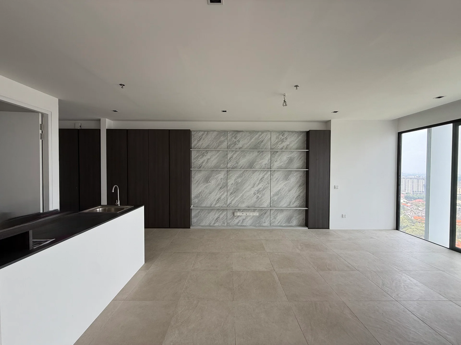 Living features: large floor-to-ceiling windows, grey marble accent wall, dark wood cabinetry, white painted walls, light-coloured tile flooring, open layout, kitchen island with sink, built-in shelving; style: modern; view: city.