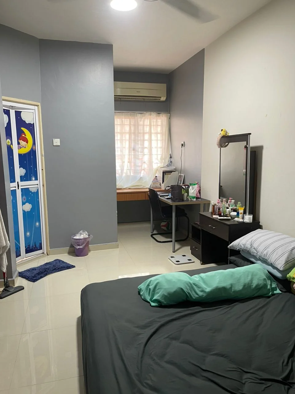 Bedroom features: grey painted walls, white ceiling, wall-mounted split AC, floor-to-ceiling window with sheer curtains, queen-size bed with dark bedding, study desk with chair, built-in wardrobe with sliding doors, tile flooring, decorative mirror, wastebasket, area rug; style: modern.