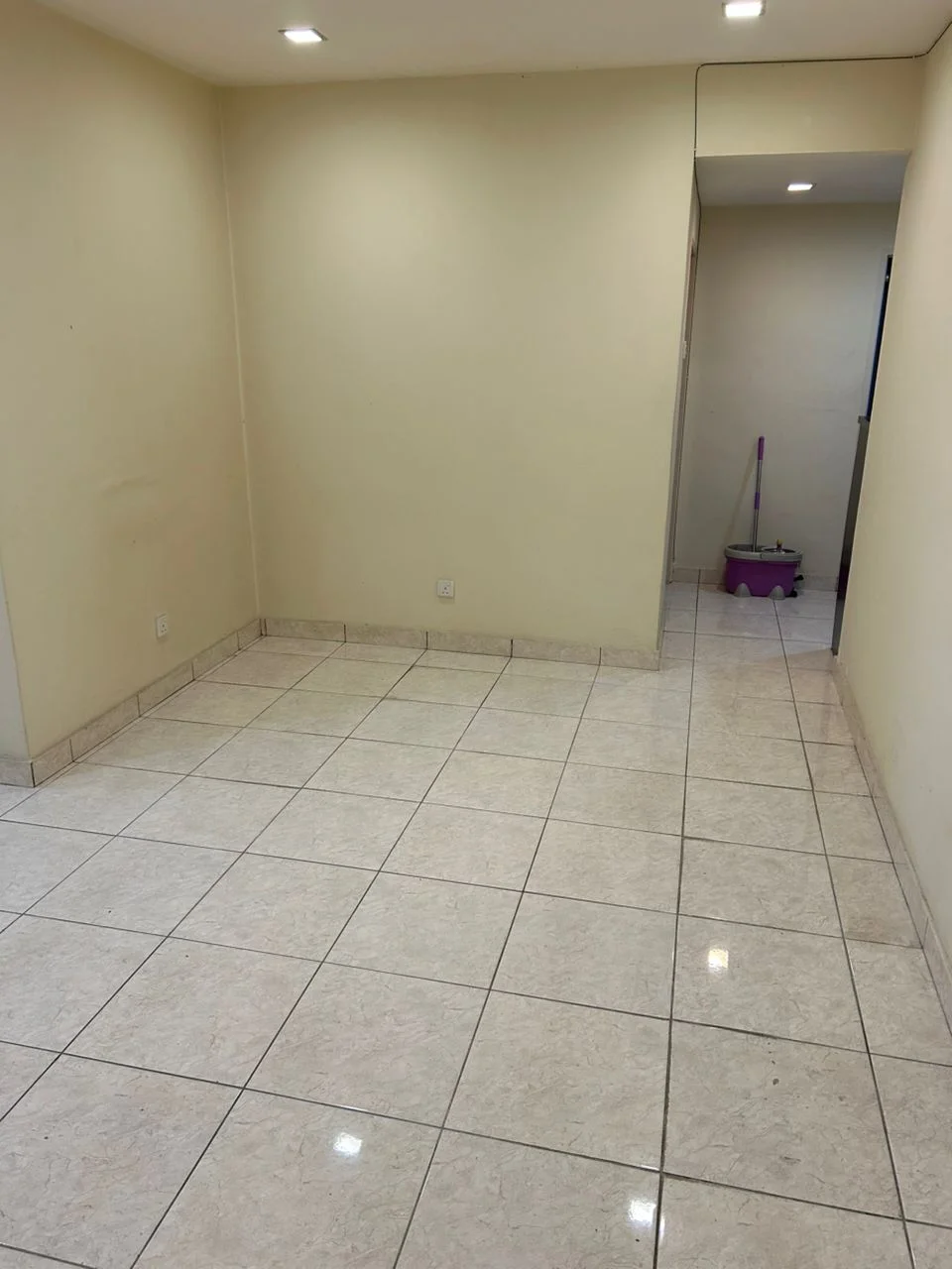 Room features: cream painted walls, glossy ceramic tile flooring, recessed downlights, no visible furniture, open layout, neutral color scheme, clean and uncluttered space; style: minimalist.