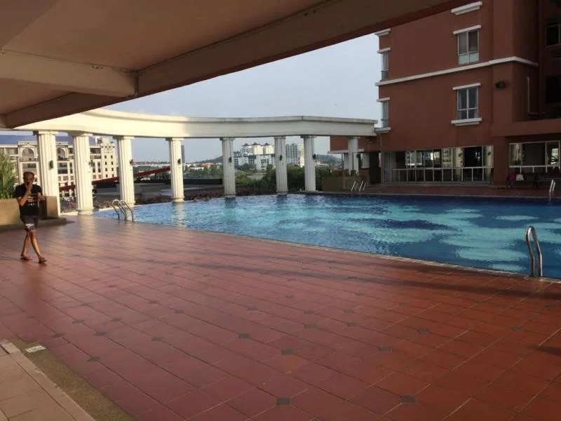 Exterior type: swimming pool deck; features: infinity pool, pool deck with loungers, surrounding tiled flooring, columns supporting the roof, landscaped area in background, view of adjacent buildings; style: modern.