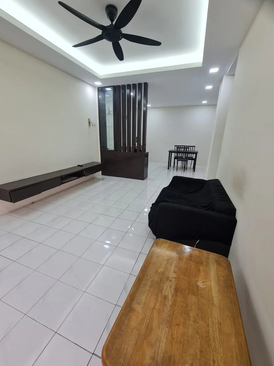 Living features: white painted walls, glossy white tile flooring, 5-blade ceiling fan with light, recessed LED downlights, wooden coffee table, black fabric sofa cover, TV console with storage, dining table with chairs, decorative feature wall with vertical panels; style: modern.
