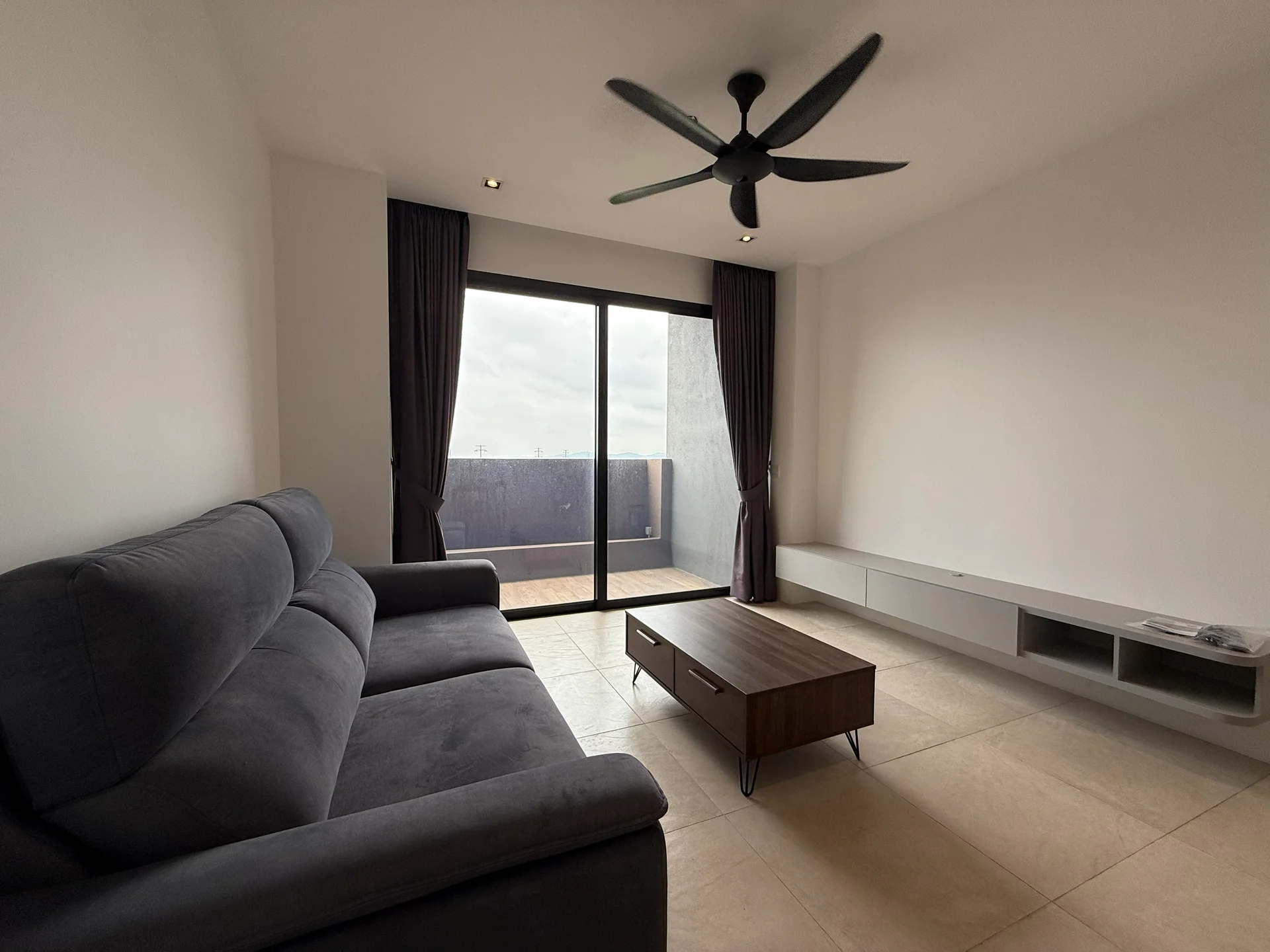 Living features: 3-seater fabric sofa in grey, wood coffee table, floor-to-ceiling sliding glass door, curtains in dark grey, recessed downlights, ceiling fan with 3 blades, light-coloured tile flooring, wall-mounted TV console; style: modern.