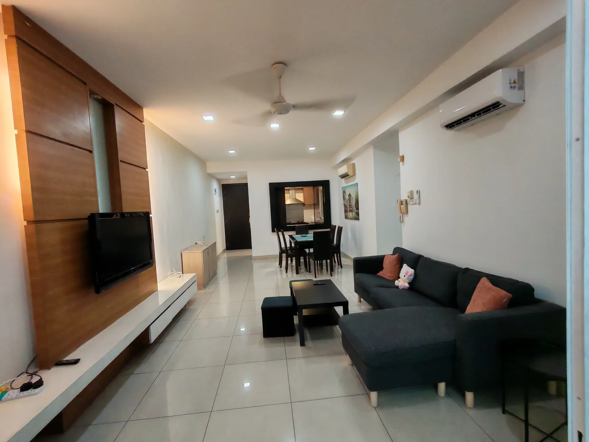 Living features: grey fabric sofa, black coffee table, wall-mounted TV, light wood TV console, cream tiled flooring, ceiling fan, recessed downlights, decorative wall with wooden panels, dining table with four chairs, air conditioning unit; style: modern.